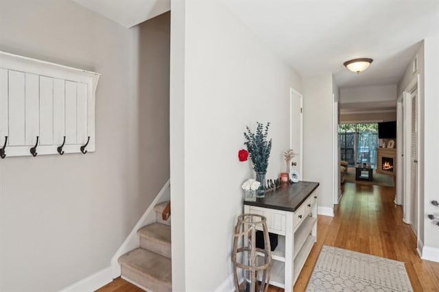 hallway featuring light wood-style flooring, stairs, and baseboards