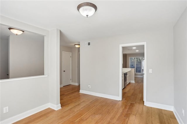 spare room featuring light wood-type flooring, visible vents, and baseboards