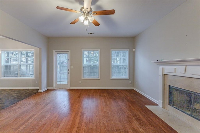 unfurnished living room featuring a premium fireplace, ceiling fan, and hardwood / wood-style flooring