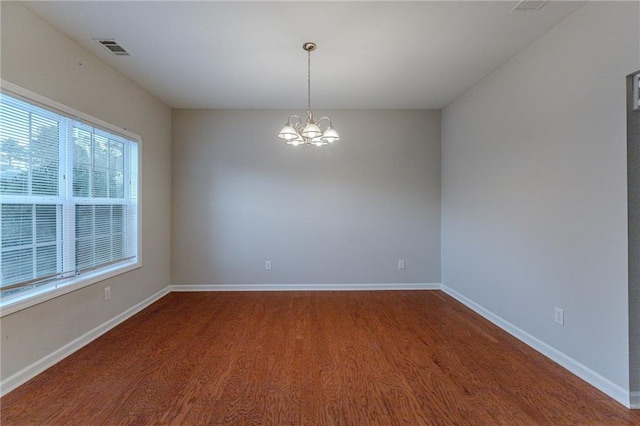 empty room with wood-type flooring and a notable chandelier