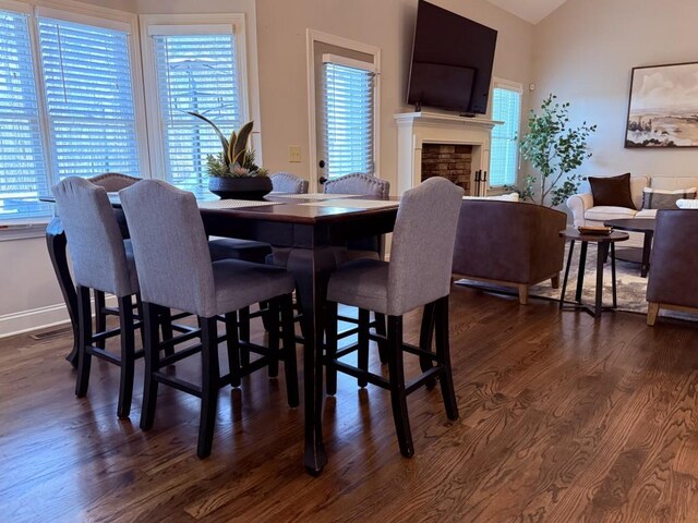 410 Spring Lake Hls, Canton, GA 30114 - dining area with dark wood-style floors, vaulted ceiling, baseboards, and a fireplace