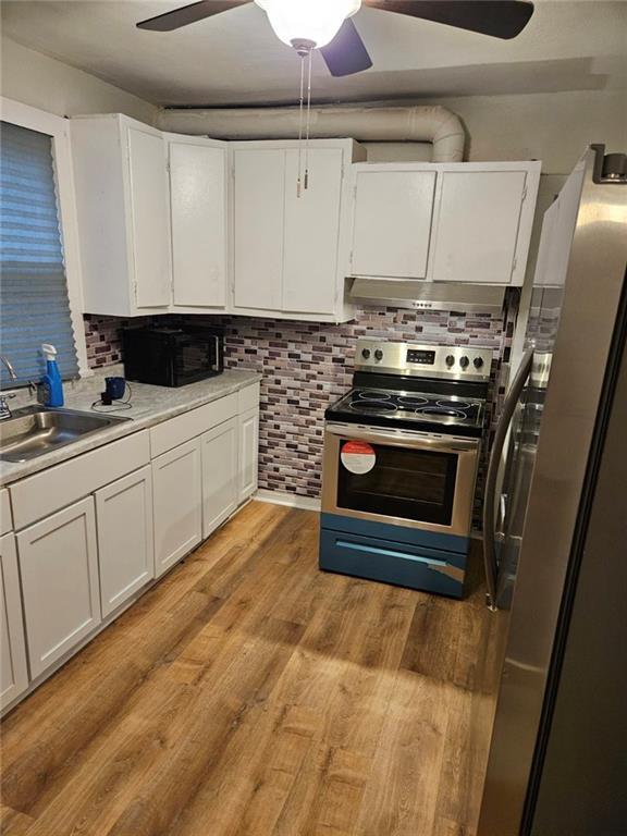 kitchen featuring sink, light hardwood / wood-style flooring, ceiling fan, stainless steel appliances, and white cabinets