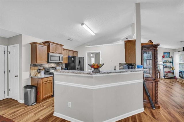 1164 Otis Dr, Bethlehem, GA 30620 - kitchen featuring stainless steel microwave, black refrigerator with ice dispenser, lofted ceiling, light wood-style flooring, and brown cabinetry