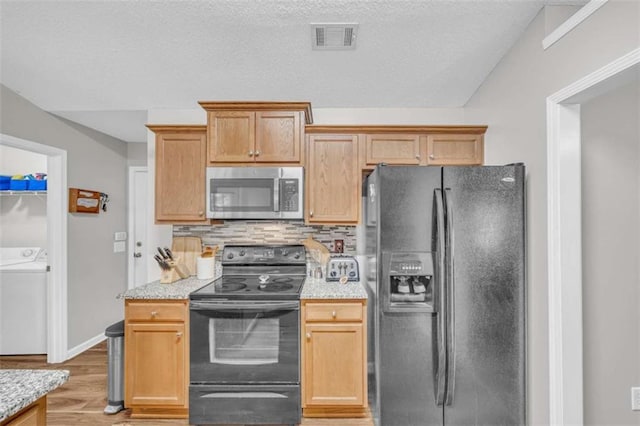 1164 Otis Dr, Bethlehem, GA 30620 - kitchen featuring black appliances, light wood-type flooring, tasteful backsplash, washing machine and clothes dryer, and light stone countertops