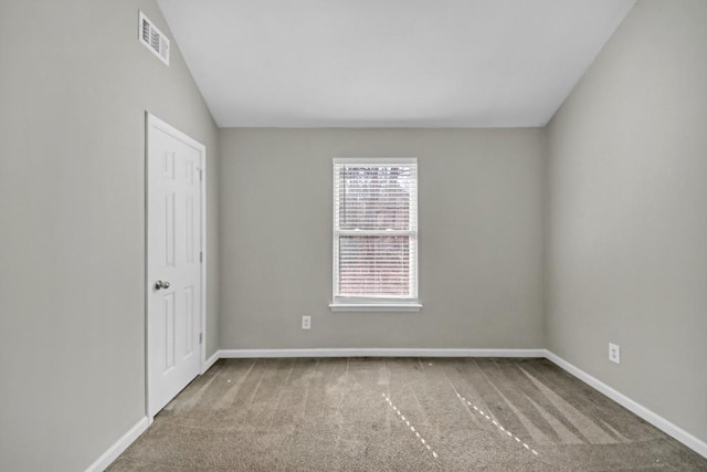 carpeted empty room featuring vaulted ceiling