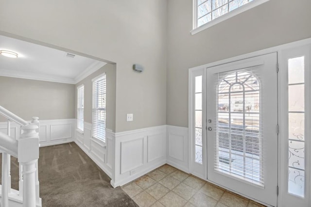 carpeted foyer entrance featuring crown molding