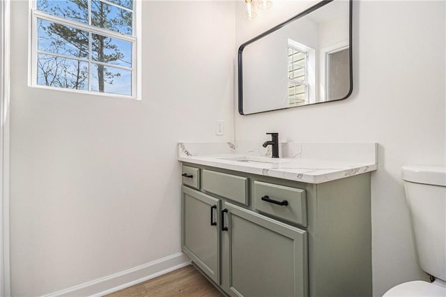 bathroom featuring toilet, wood finished floors, vanity, and baseboards