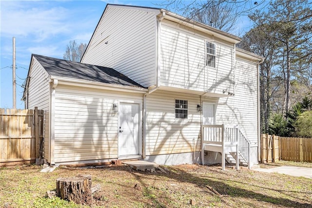 back of property with fence and a lawn