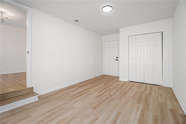 unfurnished bedroom with light wood-type flooring, a closet, visible vents, and baseboards