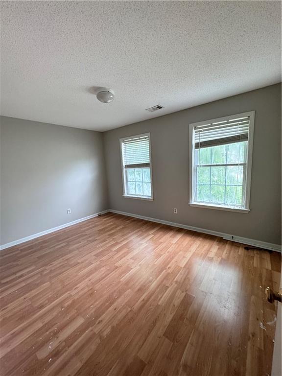 spare room with a textured ceiling and wood-type flooring