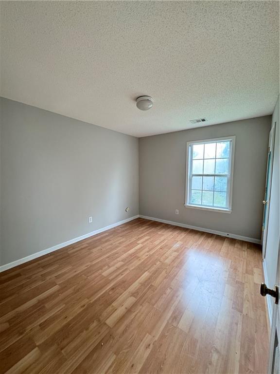 spare room featuring hardwood / wood-style floors and a textured ceiling