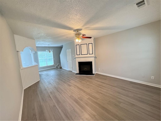 unfurnished living room with a textured ceiling, wood-type flooring, and ceiling fan with notable chandelier