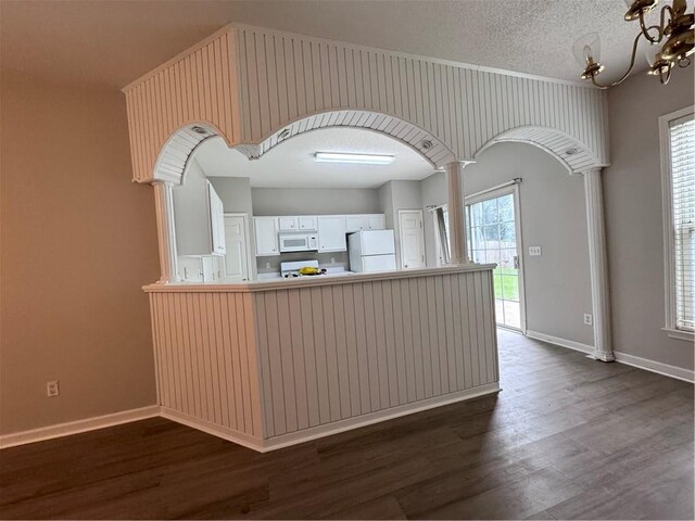 kitchen featuring dark hardwood / wood-style flooring, a textured ceiling, white cabinets, and white appliances