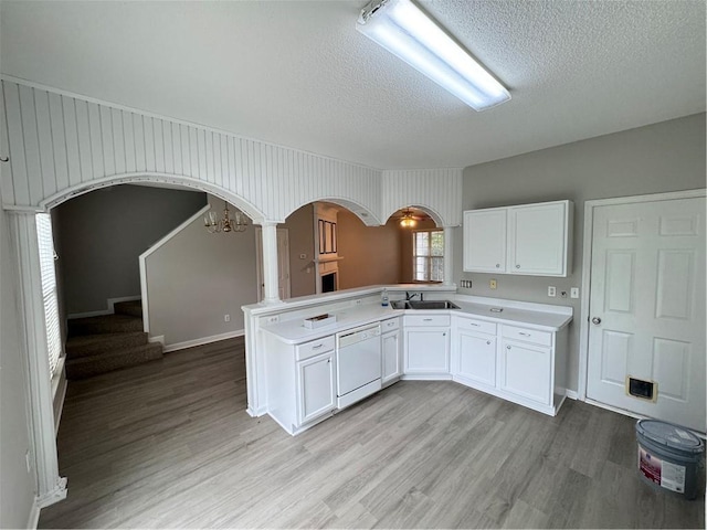 kitchen with light wood-type flooring, sink, kitchen peninsula, and white dishwasher