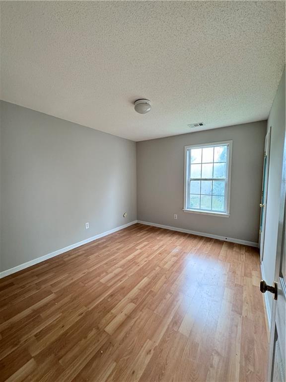 spare room featuring a textured ceiling and hardwood / wood-style flooring