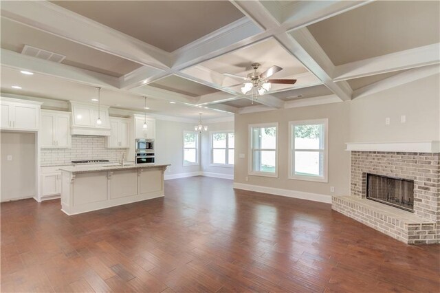 kitchen with coffered ceiling, white cabinets, hanging light fixtures, and dark hardwood / wood-style floors