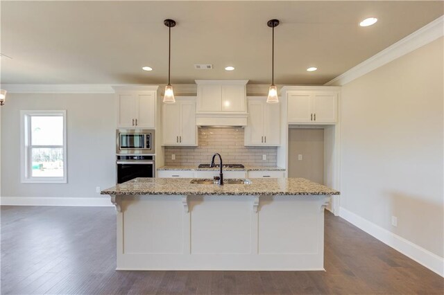 kitchen featuring a kitchen island with sink, crown molding, dark hardwood / wood-style flooring, appliances with stainless steel finishes, and light stone counters