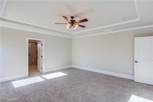 carpeted spare room with ornamental molding, ceiling fan, and a tray ceiling