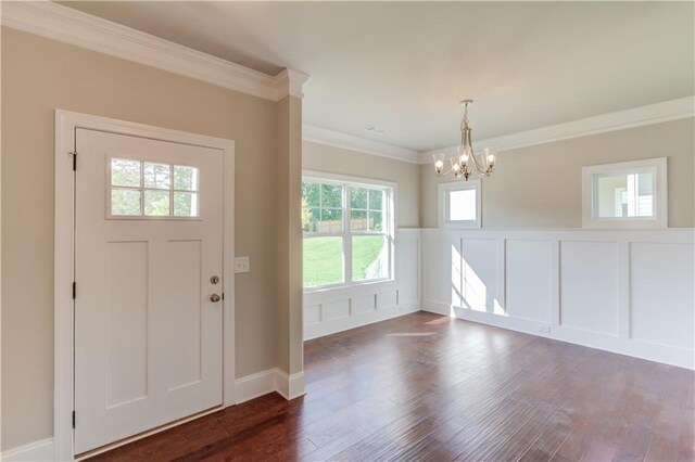 foyer entrance with ornamental molding, dark hardwood / wood-style flooring, and an inviting chandelier