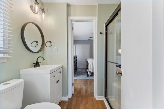 bathroom featuring hardwood / wood-style flooring, vanity, toilet, and a shower with shower door