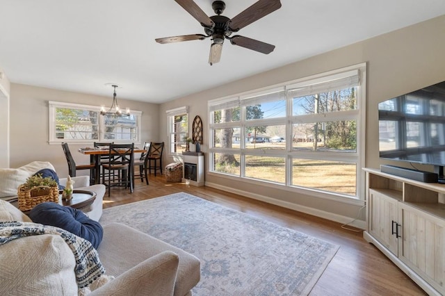 living room with ceiling fan with notable chandelier and light hardwood / wood-style flooring