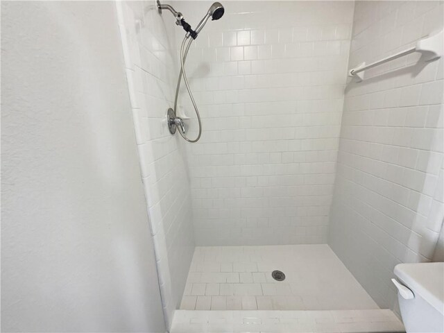 bathroom featuring tiled shower and toilet