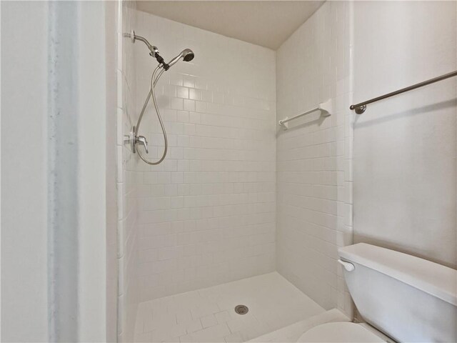 bathroom with toilet and a tile shower