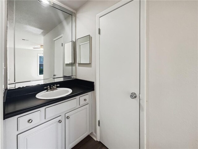 bathroom with a textured ceiling, vanity, ceiling fan, and hardwood / wood-style flooring