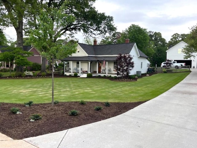 view of front facade featuring covered porch, a chimney, cooling unit, and a front yard