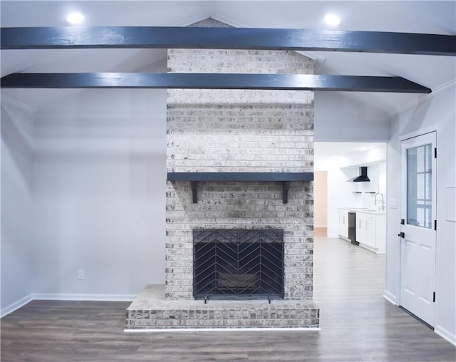 room details featuring hardwood / wood-style floors, sink, a brick fireplace, stainless steel dishwasher, and beamed ceiling