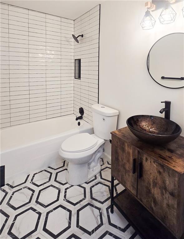full bathroom featuring tile patterned flooring, vanity, toilet, and tiled shower / bath