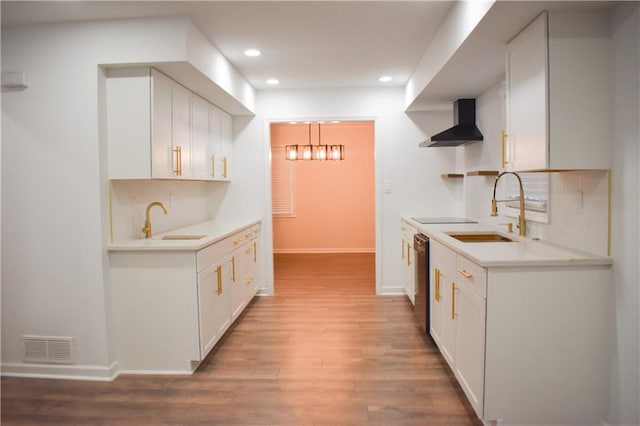 kitchen featuring black electric cooktop, white cabinetry, sink, and wall chimney range hood