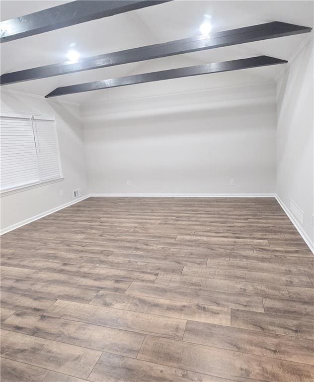 spare room featuring beamed ceiling and hardwood / wood-style flooring