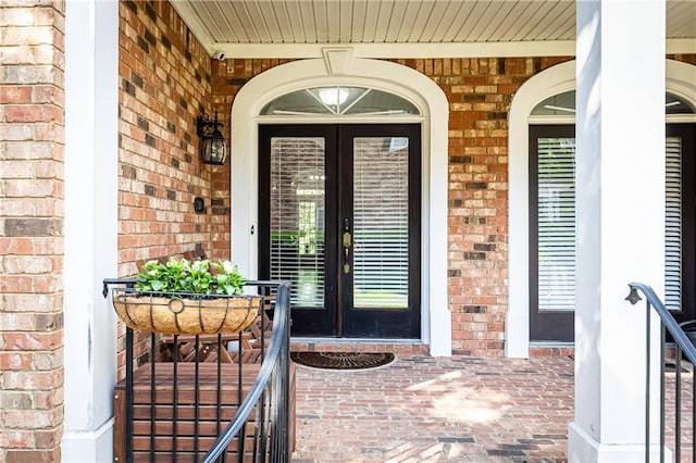 entrance to property with brick siding, french doors, and a porch