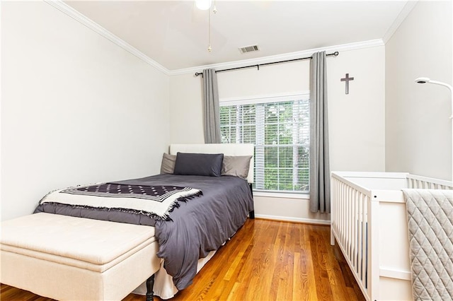 bedroom with ornamental molding, wood finished floors, and baseboards