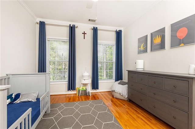 bedroom with wood finished floors, ornamental molding, multiple windows, baseboards, and ceiling fan