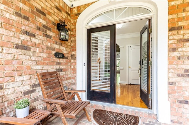 doorway to property featuring brick siding and a porch