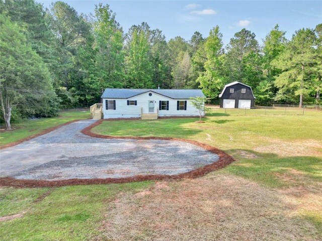 118 Buck Creek Cir, Griffin, GA 30224 - view of front of property featuring a garage, an outdoor structure, gravel driveway, a metal roof, and a forest view