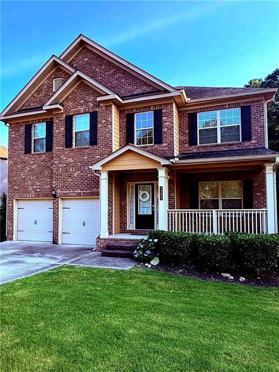 4295 Trillium Wood Trl, Snellville, GA 30039 - view of front of home with a garage, driveway, brick siding, a front lawn, and a porch