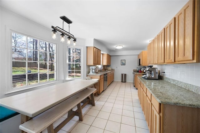 kitchen featuring a sink, appliances with stainless steel finishes, light tile patterned flooring, decorative backsplash, and light stone countertops