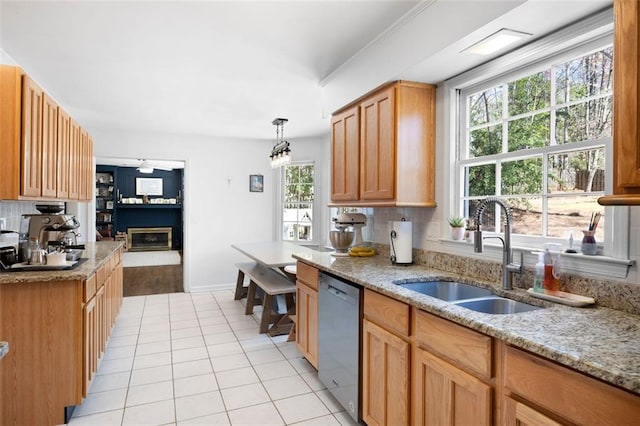 kitchen featuring a sink, tasteful backsplash, stainless steel dishwasher, a glass covered fireplace, and light tile patterned floors