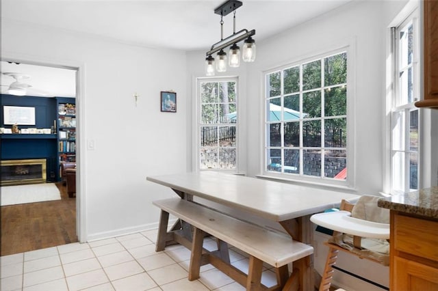 dining room with a glass covered fireplace, light tile patterned floors, baseboards, and breakfast area