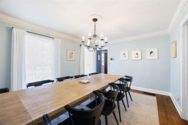 dining room with a notable chandelier, wood finished floors, baseboards, and ornamental molding