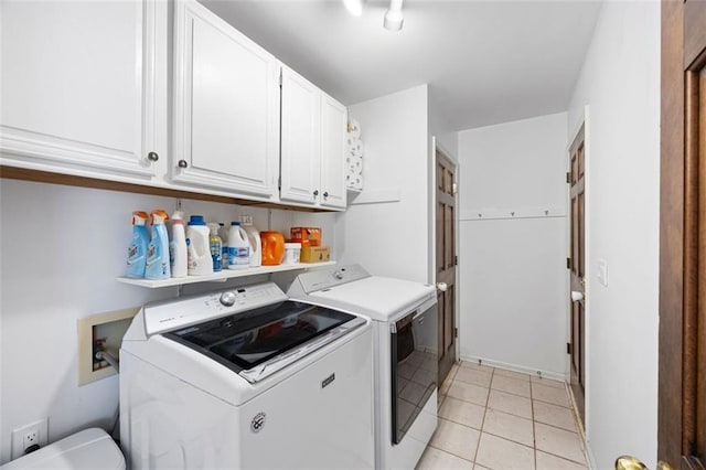 clothes washing area featuring light tile patterned floors, cabinet space, and washer and clothes dryer