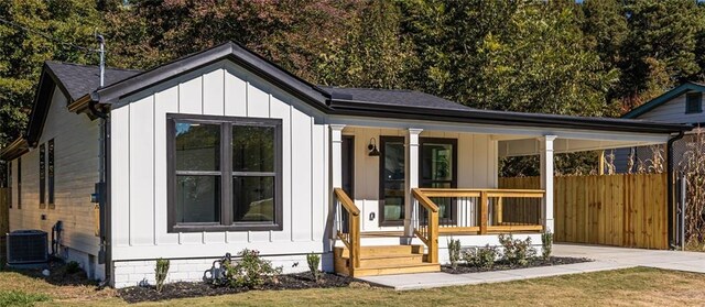 view of outdoor structure featuring central AC, a porch, and a lawn