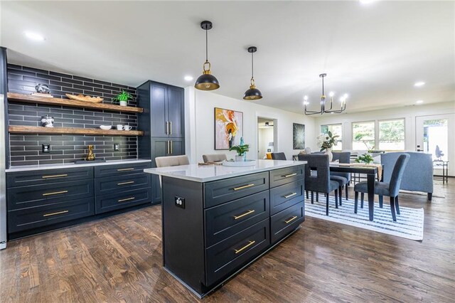 kitchen with hanging light fixtures, a kitchen island, dark wood-type flooring, and backsplash