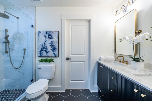 bathroom with vanity, a tile shower, toilet, and tile patterned flooring