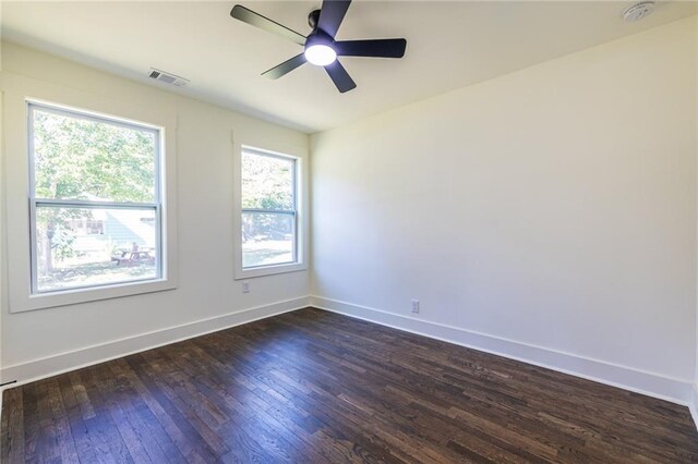 empty room featuring a wealth of natural light, dark hardwood / wood-style floors, and ceiling fan