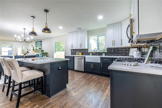 kitchen featuring a breakfast bar, white cabinetry, stainless steel appliances, pendant lighting, and a center island