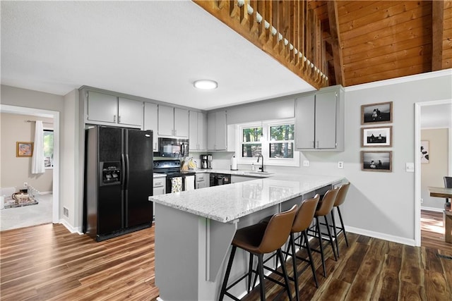 kitchen with sink, dark wood-type flooring, gray cabinets, black appliances, and kitchen peninsula